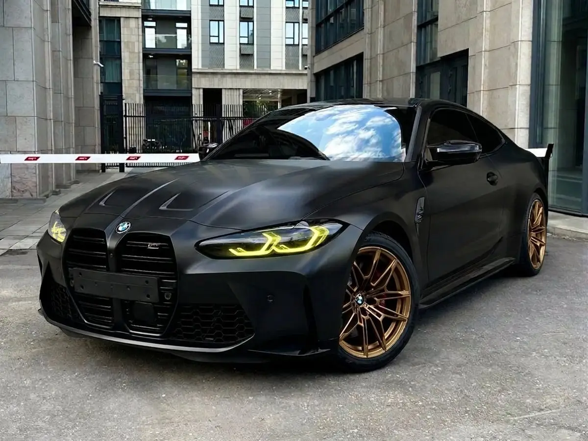 Та же BMW M4 после примерки: сатиновый чёрный, бронзовые диски, жёлтые ходовые огни, тонировка